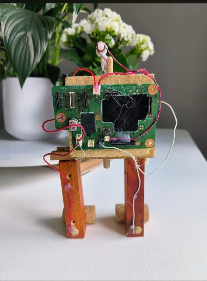 A small four-legged creature built from a salvaged green circuit board, wooden offcuts, corks and coloured wire